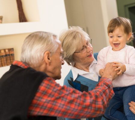 Smiling senior couple playing with their grandchild at home